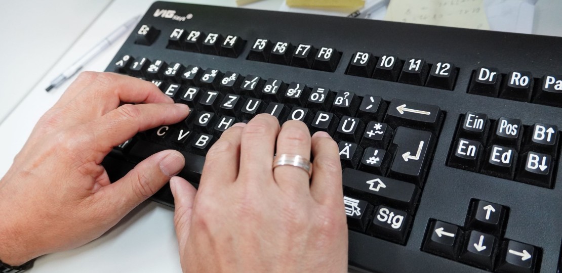 Zwei Hände an einer Großschrifttastatur