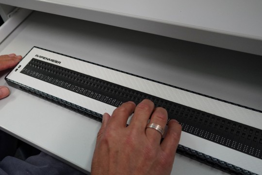 Eine Hand auf einer Braillezeile in Nahaufnahme